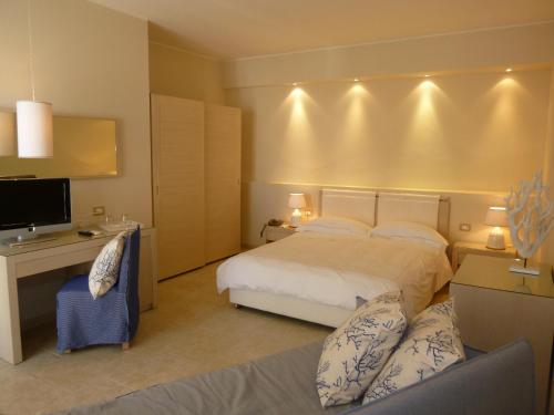 een slaapkamer met een bed, een bureau en een televisie bij Tempo Di Mare in Favignana