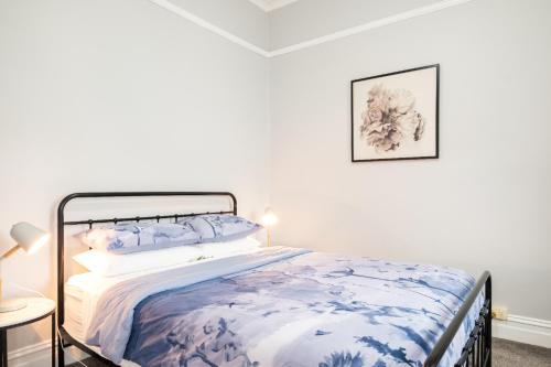 a bedroom with a bed with a blue and white comforter at Quartz Cottage Geelong in Geelong
