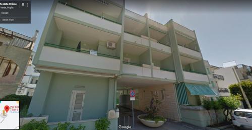 un bâtiment vert avec un balcon dans une rue dans l'établissement Casa Vacanze Iris (Baia Verde), à Baia Verde