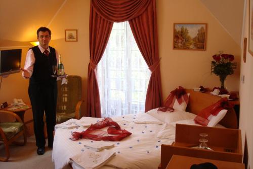 a man standing next to a bed in a room at Penzión Zlatý Jeleň in Košice