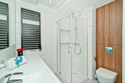 a white bathroom with a shower and a toilet at BlueApart Apartamenty Na Klifie in Władysławowo