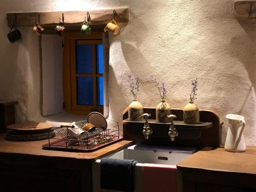 una cucina con un lavandino con vasi sul bancone di Thistle Thatch Cottage and Hot Tub - Mourne Mountains a Newcastle