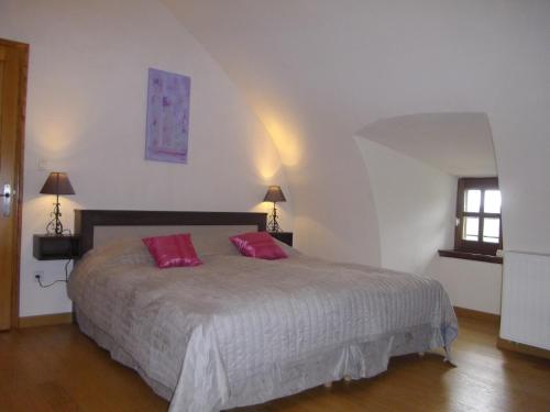 1 dormitorio con 1 cama grande y 2 almohadas rosas en Gîte les Hortensias en Le Massegros