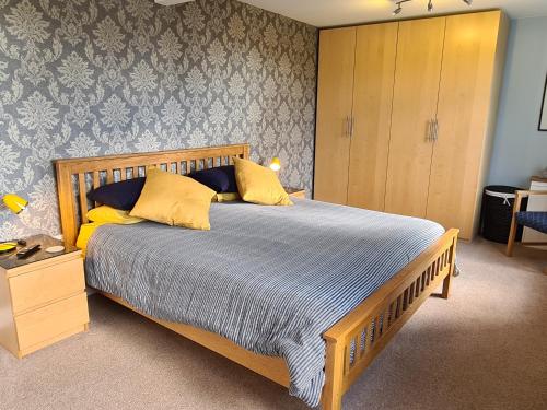 a bedroom with a wooden bed with yellow pillows at Owl Barn Sisland - spacious apartment in Norwich