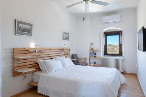a bedroom with a bed with a wooden headboard and a window at Wind Tales in Ermoupoli