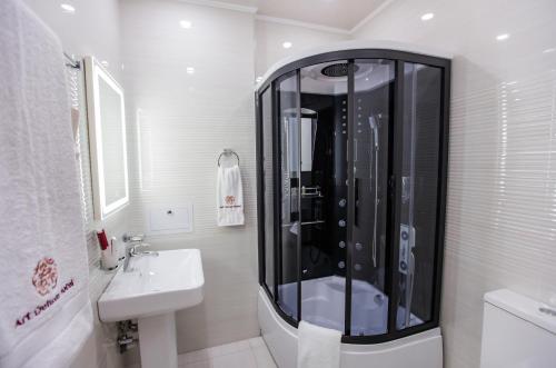 uma casa de banho branca com um chuveiro e um lavatório. em Art Deluxe Hotel em Tashkent