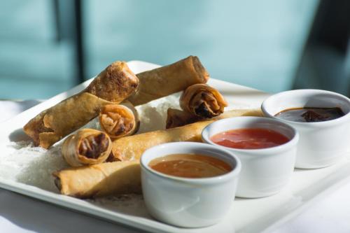 a plate of food with two cups of dipping sauces at Holiday Inn Muscat AlSeeb by IHG in Muscat