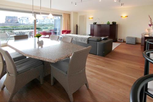 a dining room and living room with a table and chairs at Fairway Apartment in Knokke-Heist