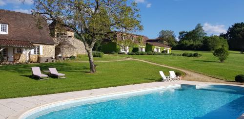 - une piscine avec 2 chaises longues et une maison dans l'établissement Le Clos-Lascazes maison d'Hôtes, au Buisson de Cadouin
