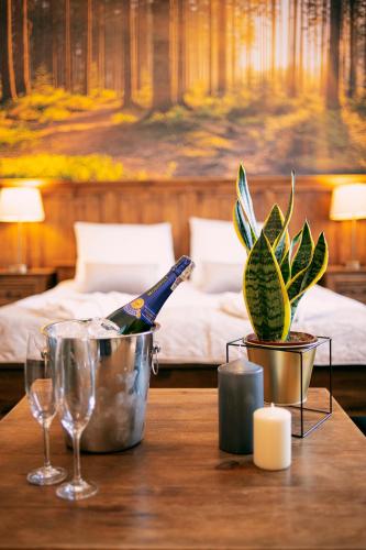 a table with a bottle of wine and a potted plant at Hotel Kotarz Spa&Wellness in Brenna
