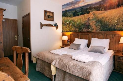 a bedroom with a bed with a painting on the wall at Hotel Kotarz Spa&Wellness in Brenna