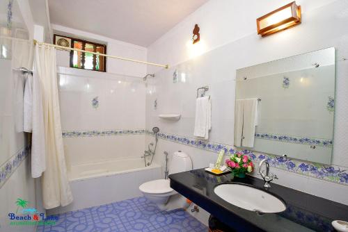 e bagno con lavandino, servizi igienici e vasca. di Beach and Lake Ayurvedic Resort, Kovalam a Kovalam