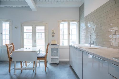 a white kitchen with a sink and a table at Altes Kontorhaus Backbord in Husum