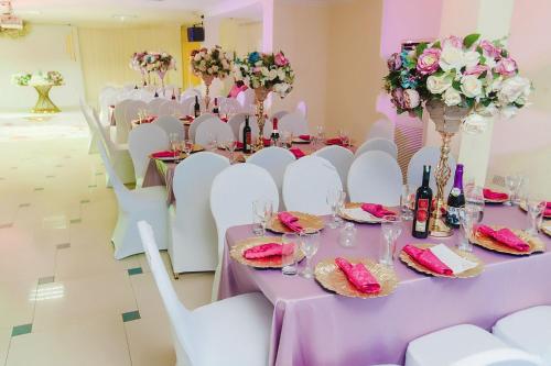 a room with a table with white chairs and flowers at Korkdam Hotel in Achimota