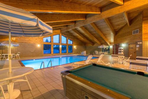 a pool in a room with a pool table and an umbrella at AmericInn by Wyndham Minocqua in Minocqua