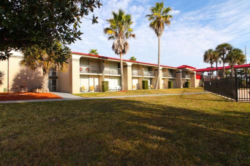a building with palm trees in front of it at Ramada by Wyndham Davenport Orlando South in Davenport