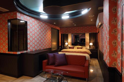 Habitación de hotel con cama y sofá rojo en Himeji Park Hotel (Adult Only) en Himeji