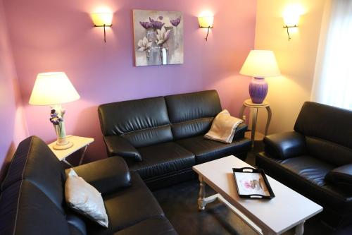 a living room with black leather furniture and purple walls at Hotel de la Jamagne & Spa in Gérardmer