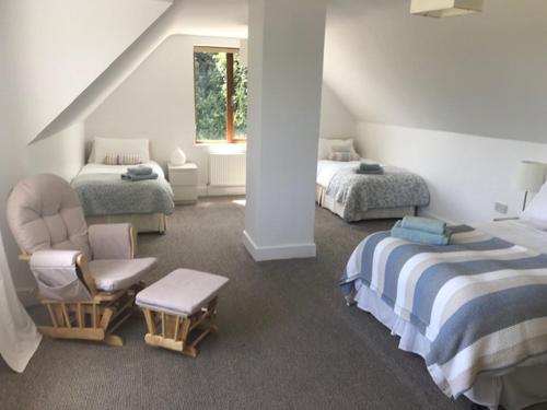 a attic bedroom with two beds and a chair at Tinnaberna Lodge Kilmuckridge in Kilmuckridge