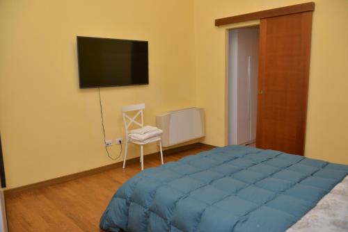 um quarto com uma cama azul, uma cadeira e uma televisão em RIETINN em Rieti