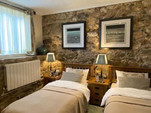 two beds in a room with stone walls at Casa Camino Turismo Rural in Palas de Rei 