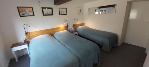 two beds in a hotel room with blue sheets at La Fermette Blanche in Nadrin