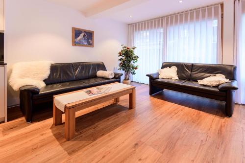 a living room with two leather couches and a coffee table at Jolimont Apartments in Zermatt
