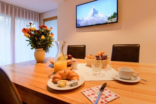 a table with a breakfast of croissants and juice at Jolimont Apartments in Zermatt