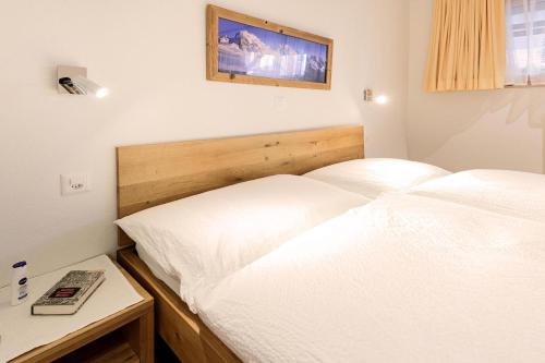 a bedroom with two white beds and a table at Jolimont Apartments in Zermatt