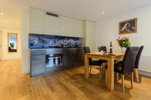 a dining room with a table and a kitchen at Jolimont Apartments in Zermatt