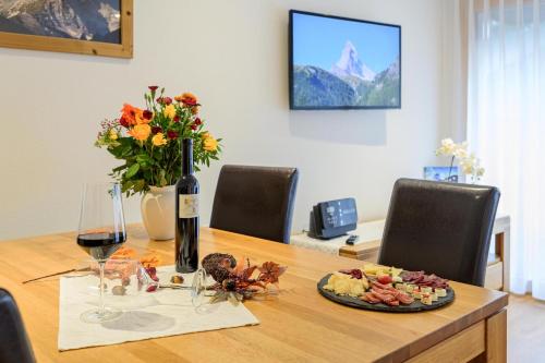 a table with a bottle of wine and a plate of food at Jolimont Apartments in Zermatt