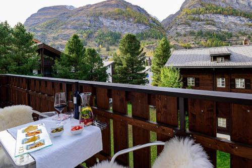 a table with food and wine on a balcony with mountains at Jolimont Apartments in Zermatt