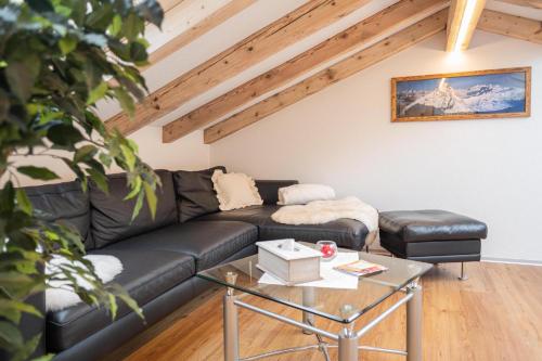 a living room with a black leather couch and a table at Jolimont Apartments in Zermatt