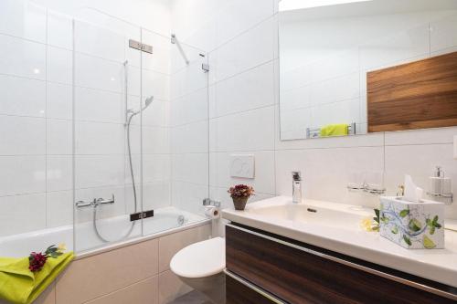 a bathroom with a sink and a tub and a toilet at Jolimont Apartments in Zermatt