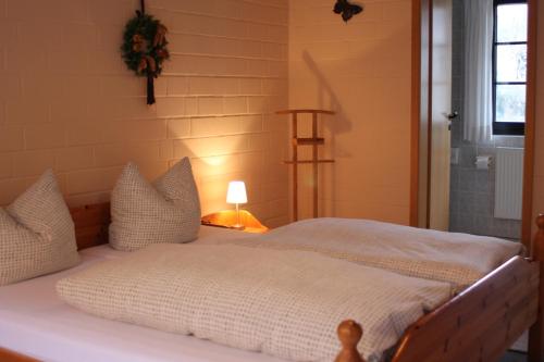 1 cama con sábanas blancas y almohadas en una habitación en Landhotel Belitz Garni, en Küsten