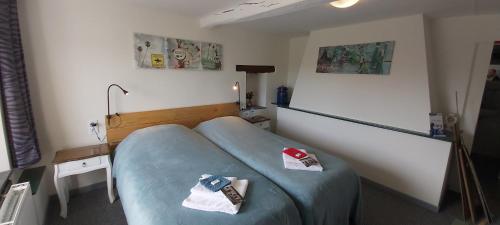 a bedroom with a blue bed with a remote control on it at La Fermette Blanche in Nadrin