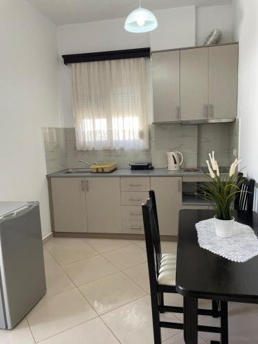 a kitchen with a dining table and a kitchen with white cabinets at Relax Apts Saranda in Sarandë