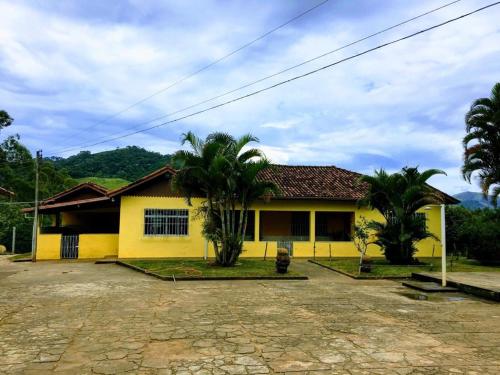 a yellow house with two palm trees in front of it at Casa/sítio na serra em Bom Jardim - RJ in Bom Jardim