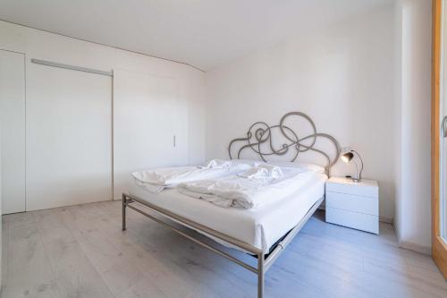 ein weißes Schlafzimmer mit einem Bett mit einem Kopfteil aus Metall in der Unterkunft Olivia Home in Caprile