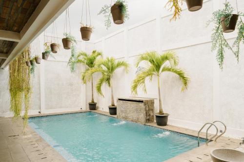 uma piscina interior com palmeiras num edifício em Otu Hostel By Ostic em Yogyakarta