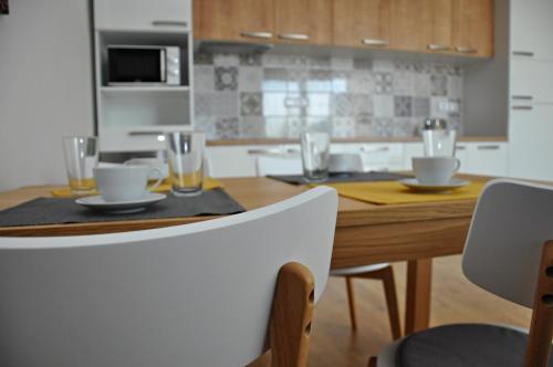 a kitchen with a wooden table with plates and glasses on it at Relax apartmán Třeboň in Třeboň