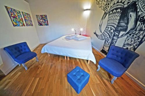 - une chambre avec un lit et deux chaises bleues dans l'établissement Maison Catalina, à Gignac