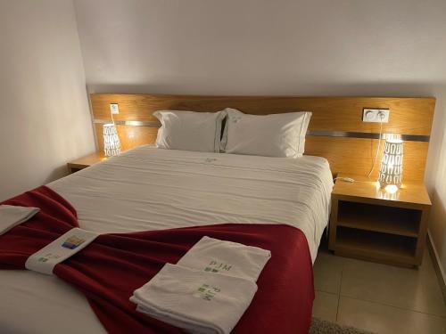 a bedroom with a large bed with red and white sheets at Gites Des Sablons in Châtillon-sur-Marne