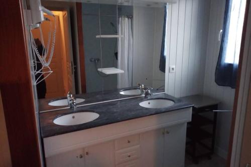a bathroom with two sinks and a large mirror at La faurie in Soubran