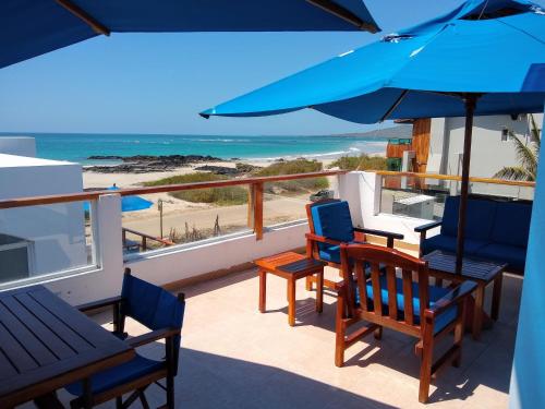 a balcony with chairs and an umbrella and the beach at Drake Inn in Puerto Villamil