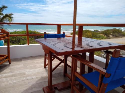 a wooden table and chairs on a balcony with the ocean at Drake Inn in Puerto Villamil