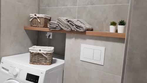a bathroom with a washing machine and baskets on a shelf at Apartament przy Onkologii in Bydgoszcz