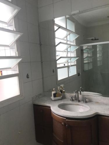 uma casa de banho com um lavatório e um espelho em Ap frente ao mar em São Paulo