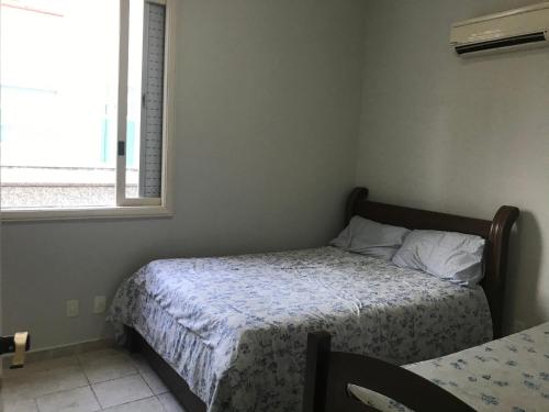 a small bedroom with a bed and a window at Ap frente ao mar in Sao Paulo