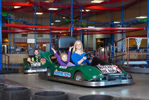 two children are riding in a green car at Staybridge Suites - Wisconsin Dells - Lake Delton by IHG in Wisconsin Dells